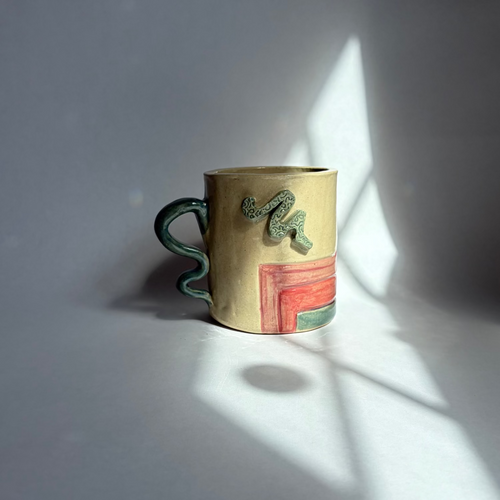 A beige mug with teal, pink, and purple accents on a white background.