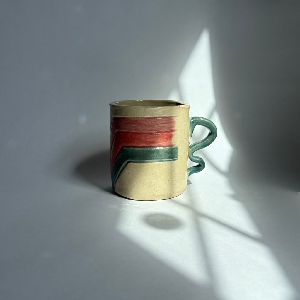 A beige mug with teal, pink, and purple accents on a white background.