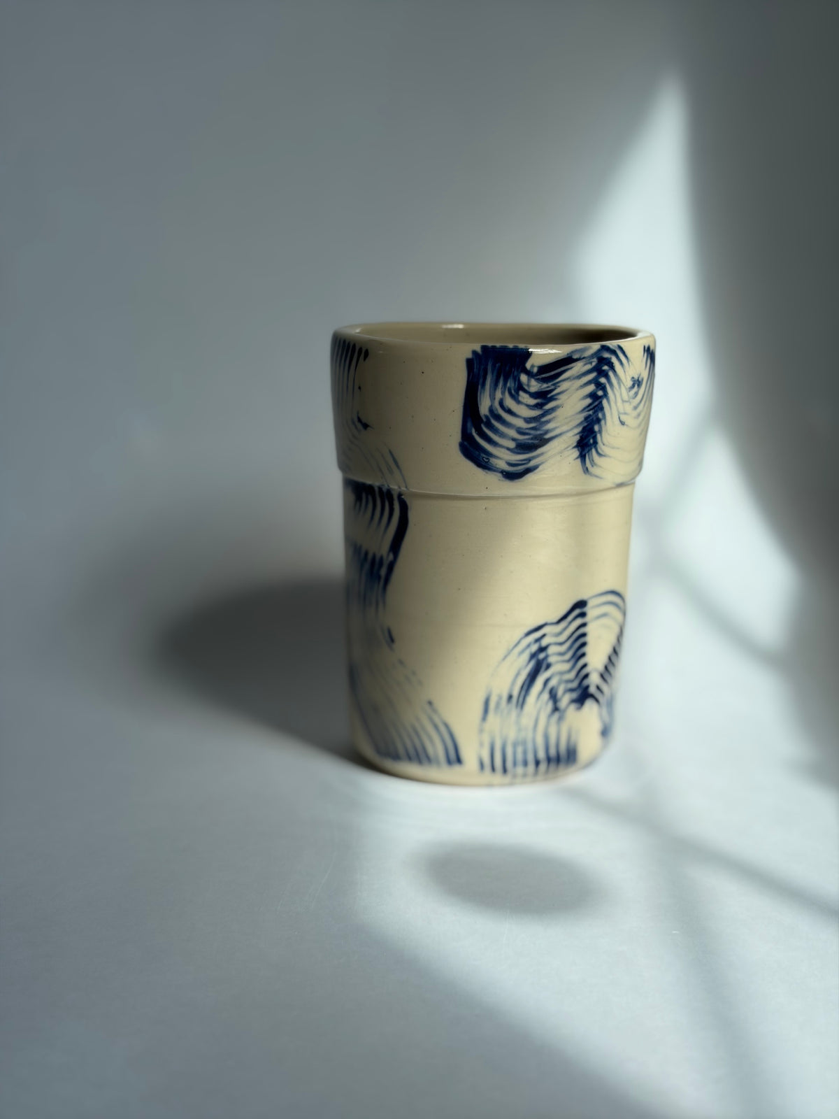 a beige tumbler with blue stripes