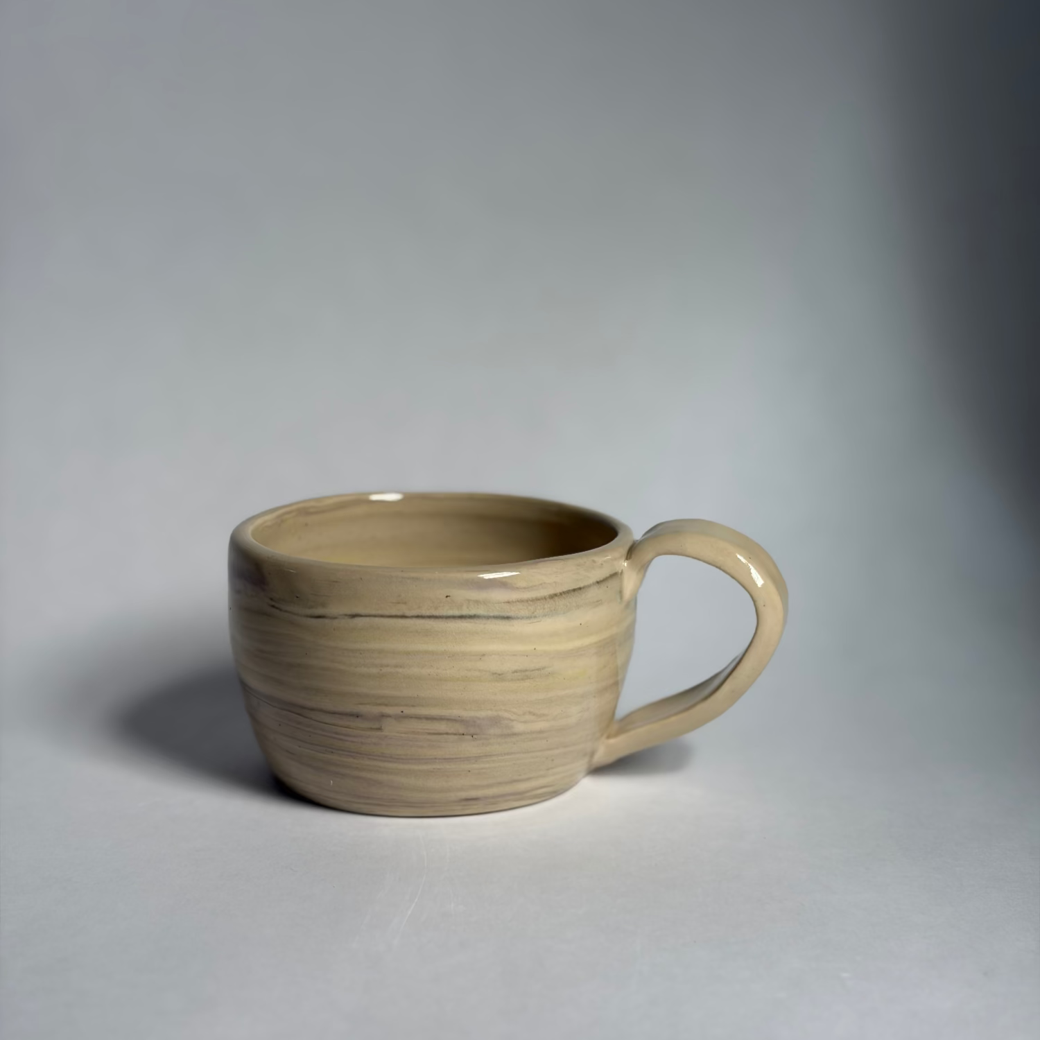 Photo of a beige mug with marbled colors against a white background.