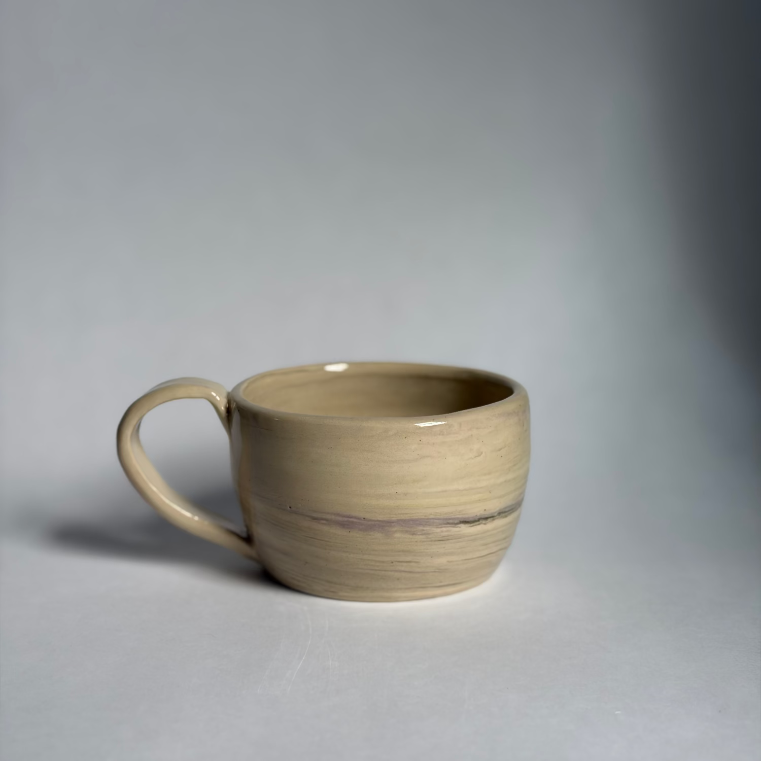 Photo of a beige mug with marbled colors against a white background.