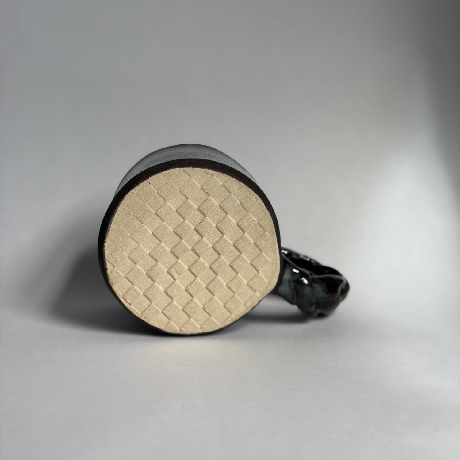 Base view of a mug with a braided handle revealing an embossed checkered pattern.