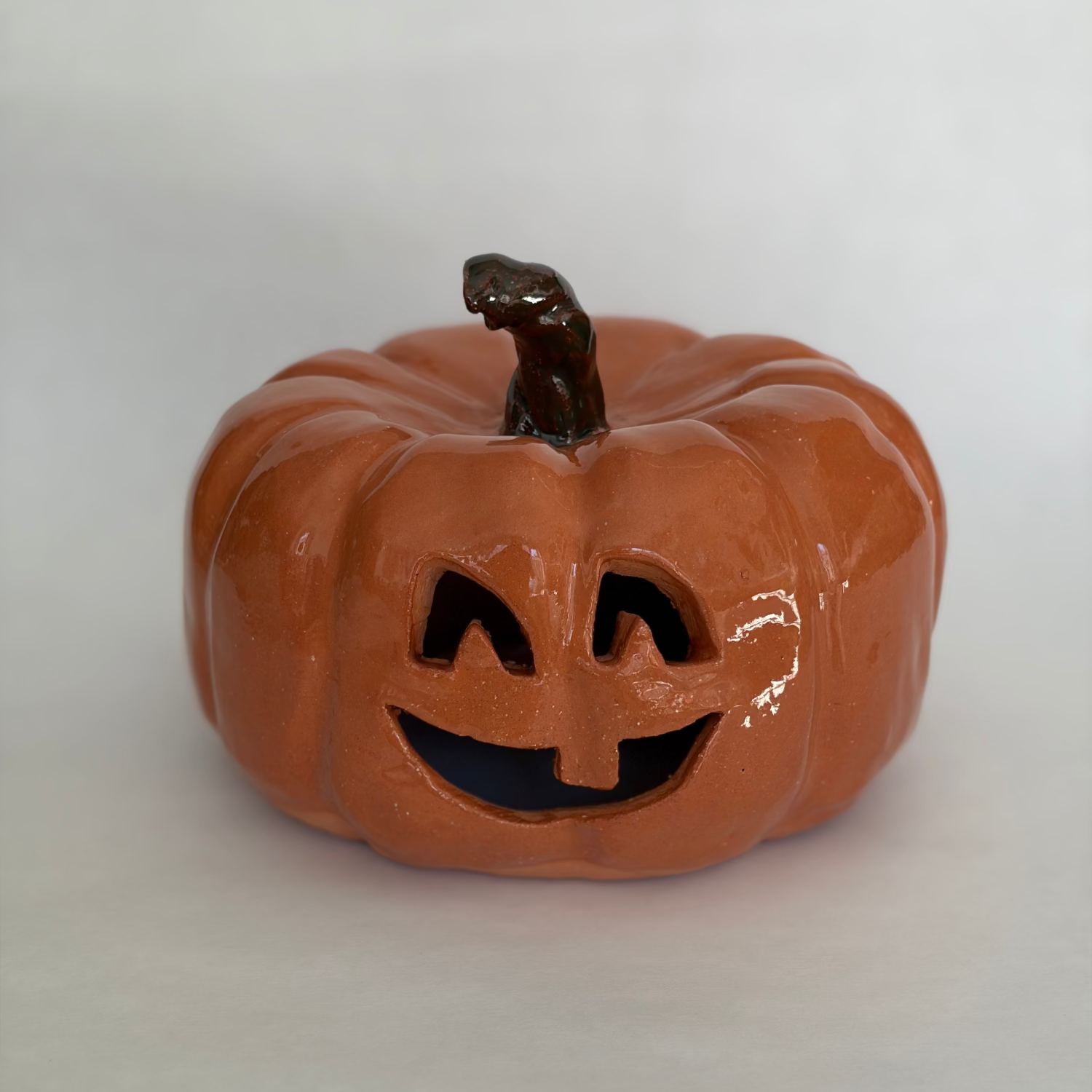 A large carved orange jack-o'-lantern pumpkin figurine with a green stem.