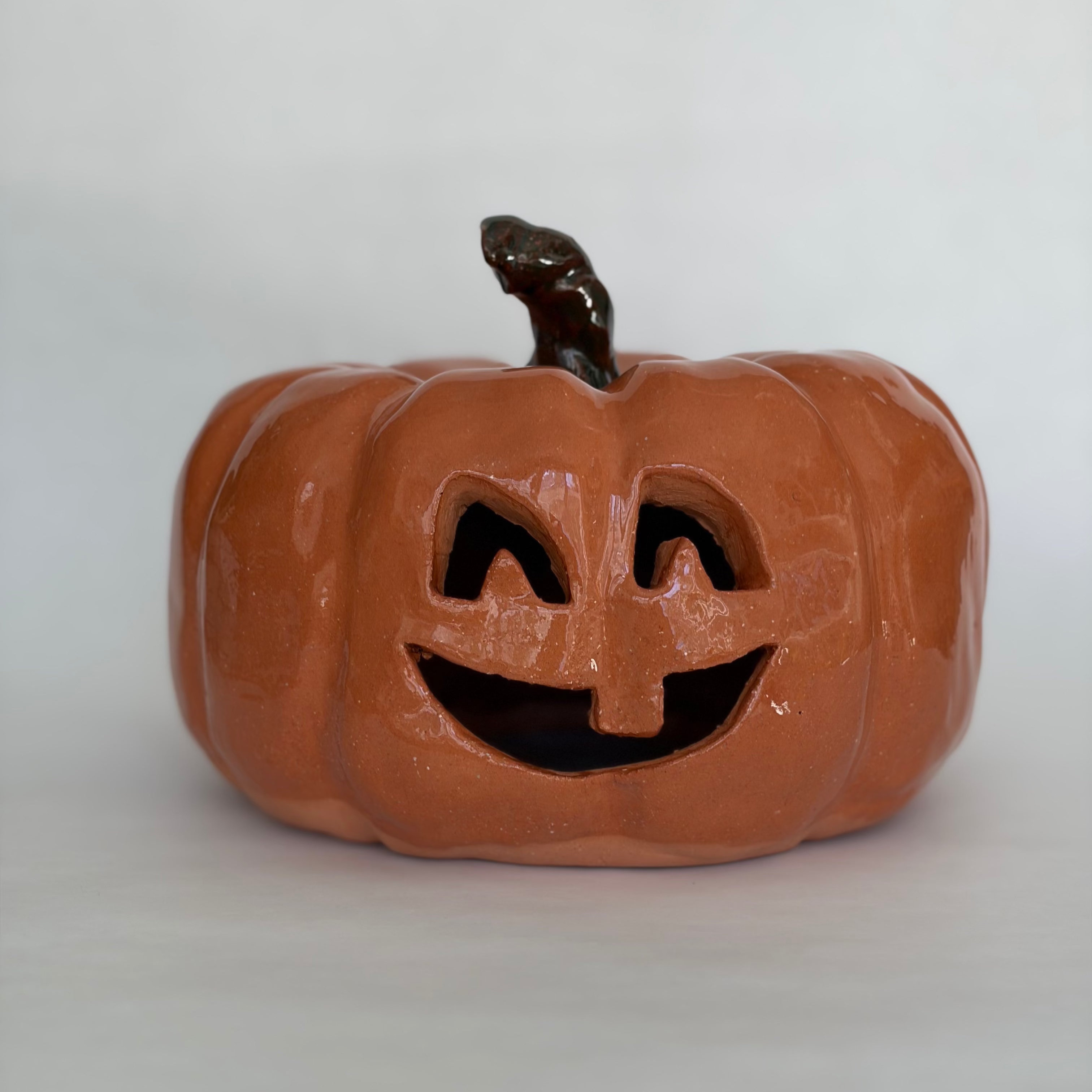 A large carved orange jack-o'-lantern pumpkin figurine with a green stem.