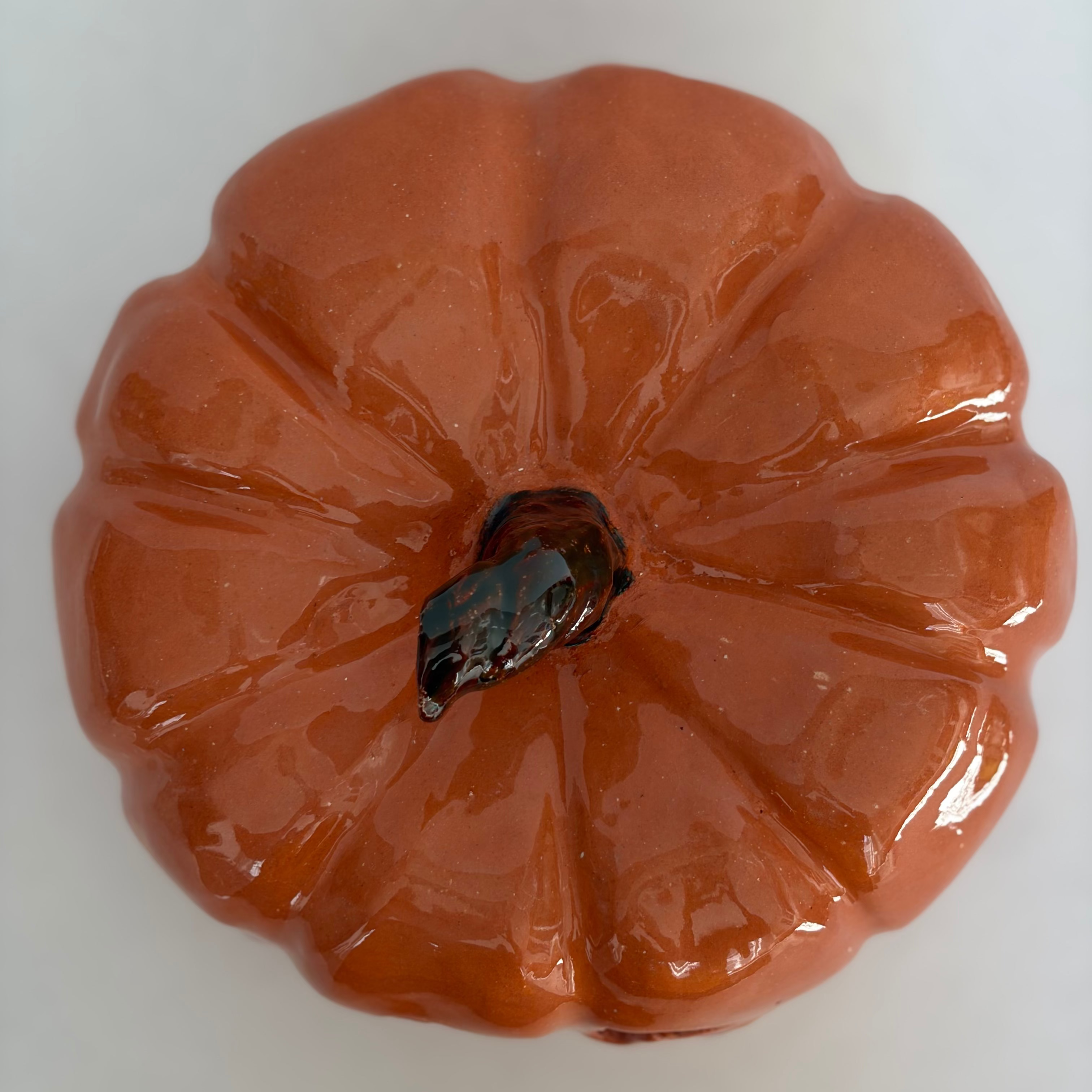 A large carved orange jack-o'-lantern pumpkin figurine with a green stem.