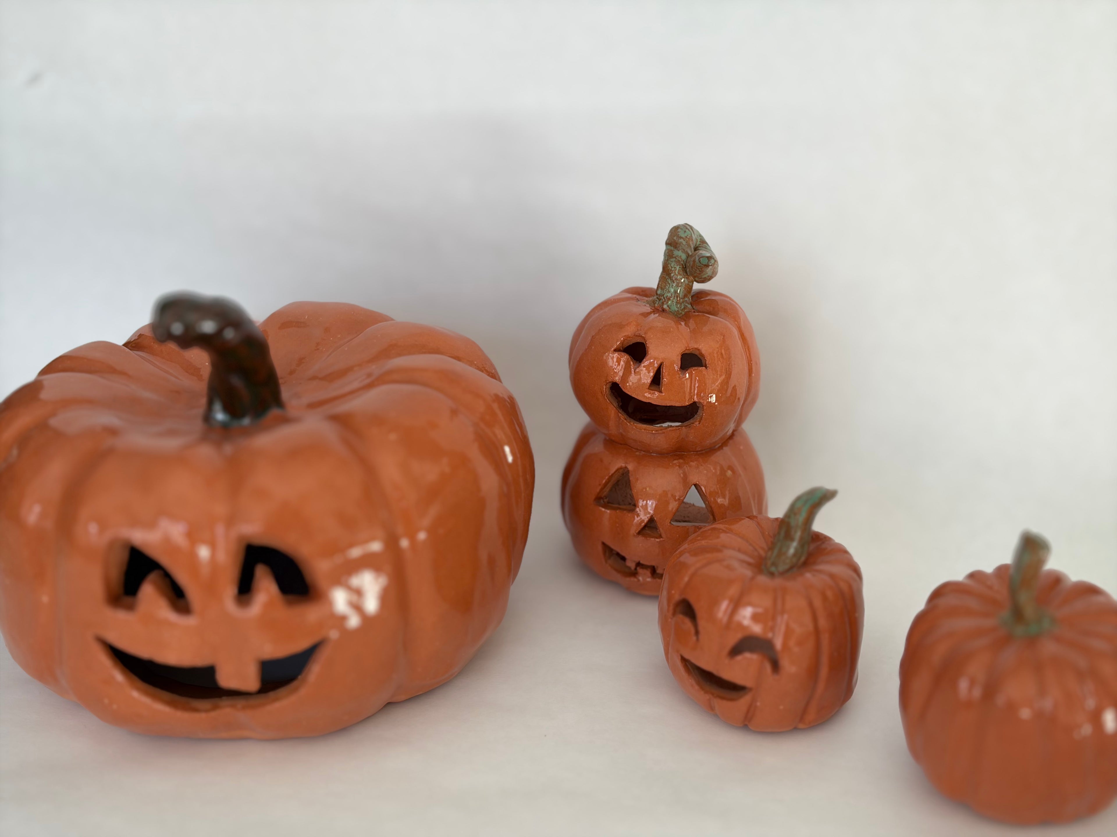 A stacked pair of joined jack-o-lantern figurines among a group of 3 other pumpkin figurines