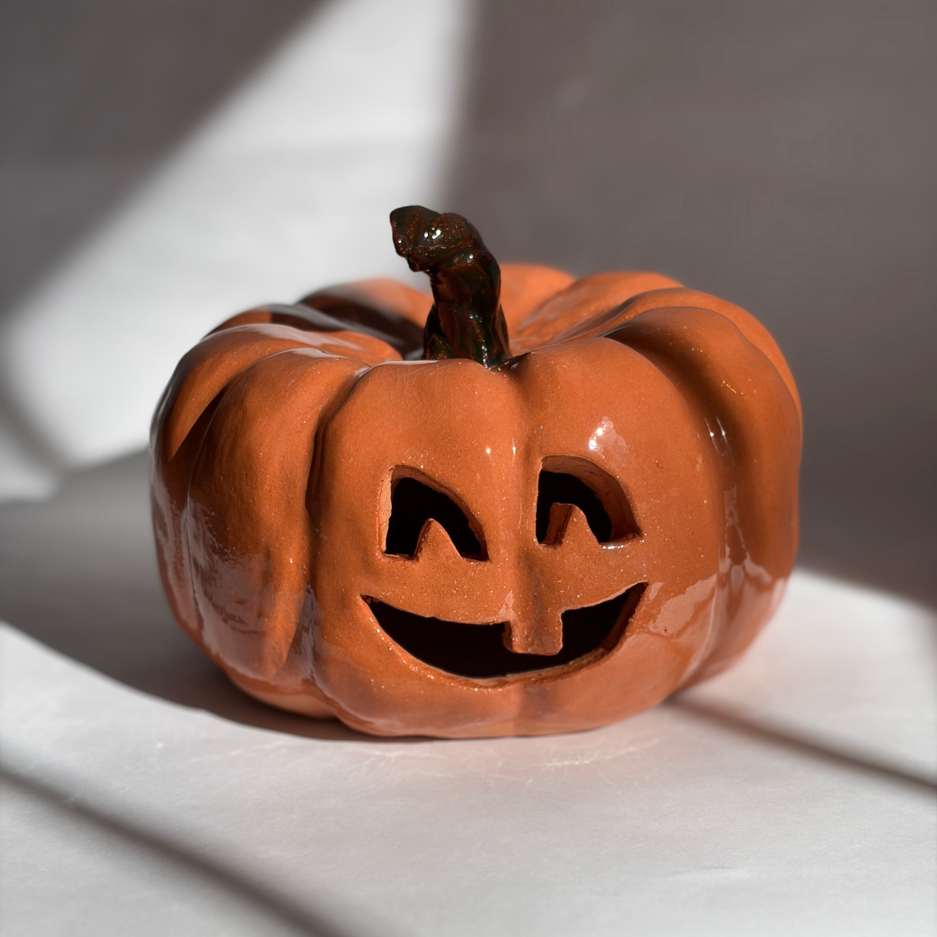 A large carved orange jack-o'-lantern pumpkin figurine with a green stem.